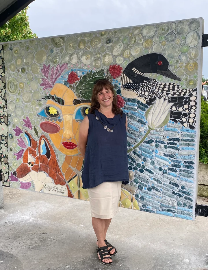 Meg Leslie standing in front of a colourful mosaic artwork