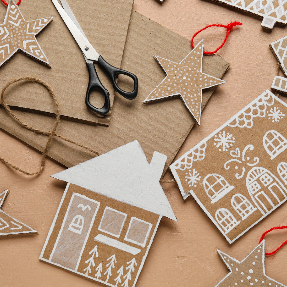 Handmade cardboard holiday houses and ornaments decorated with white painted details.